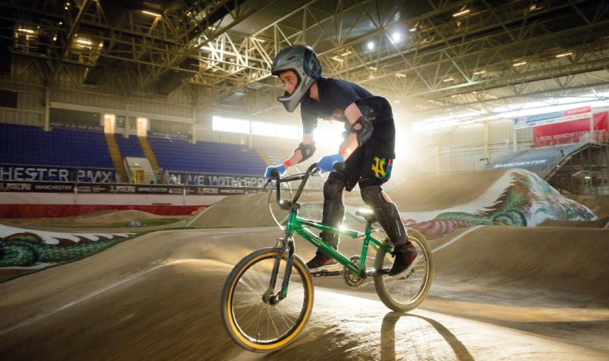 Young person on a BMX on an indoor BMX track
