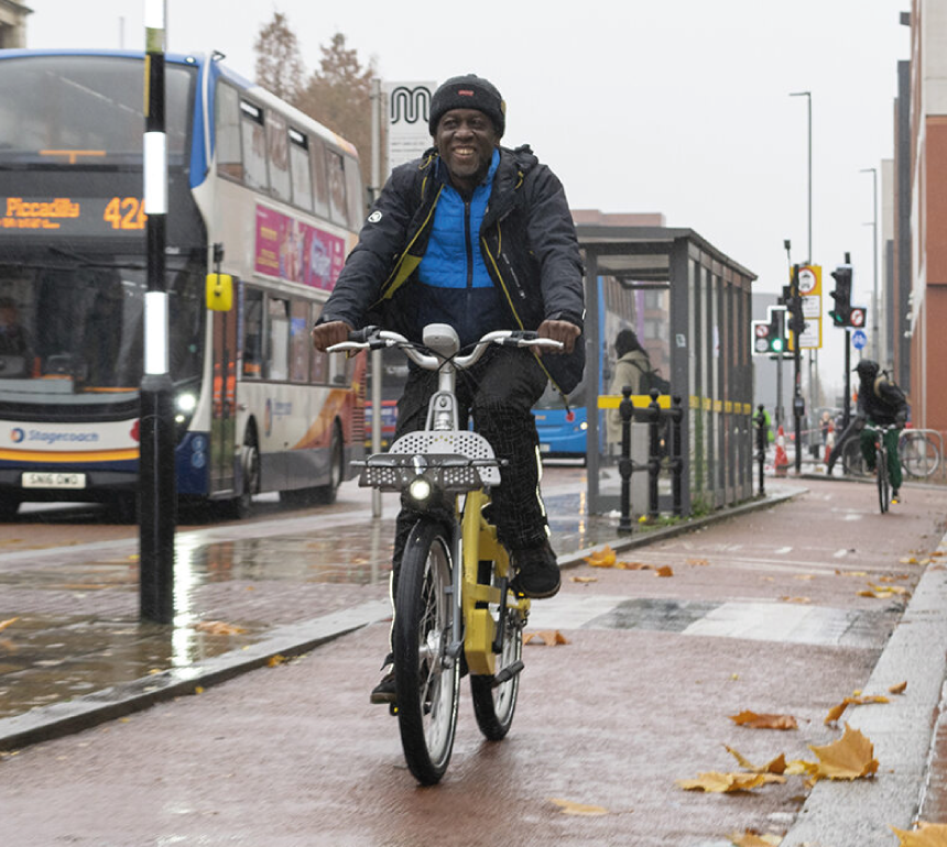 Man riding a cycle hire bike on a city centre cycle lane with bus in the background