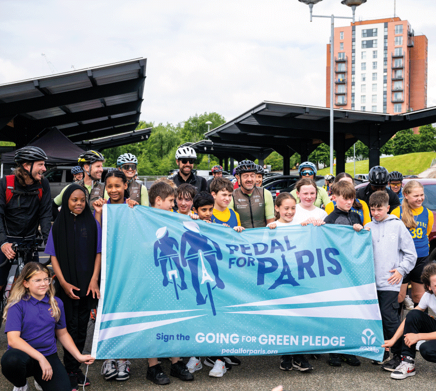 Chris Boardman and schoolkids holding Pedal for Paris sign at National Cycling Centre