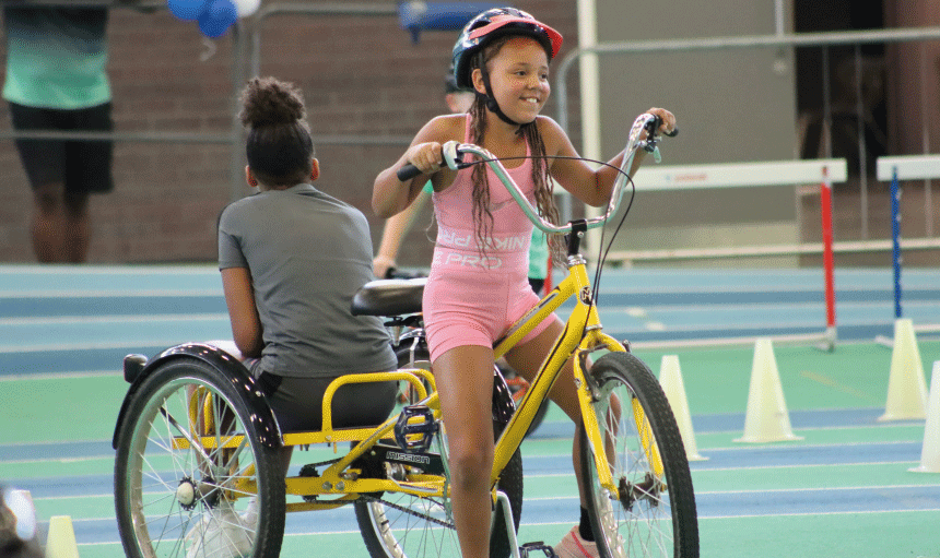 Children smiling on trike at family sports taster day event