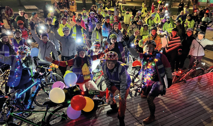 Group of women with bikes covered in lights at night time in manchester