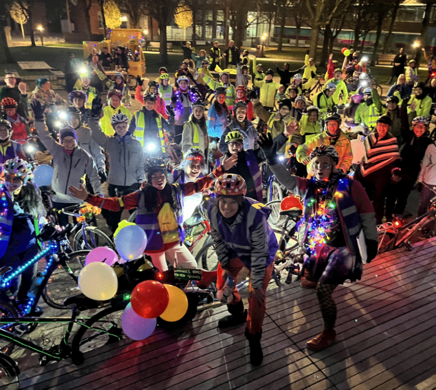 Group of women with bikes covered in lights at night time in manchester